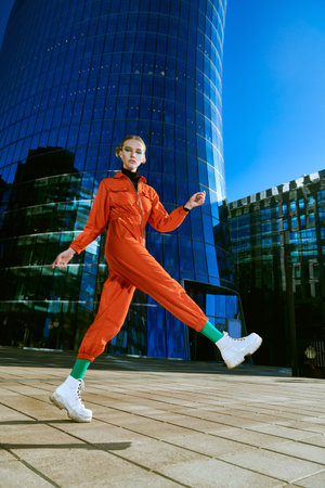 Fashion shot. Attractive young woman with bright makeup and in stylish colorful clothes posing on a...