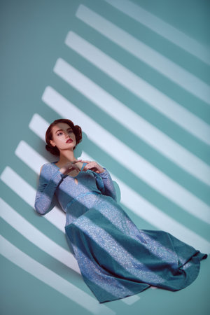 Fashion model in a long elegant dress and with hair and makeup in the style of the 20s posing in a...