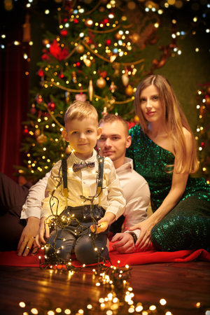 Happy parents celebrate Christmas with their beloved son in a beautiful cozy atmosphere at home. Happy family holiday.の写真素材