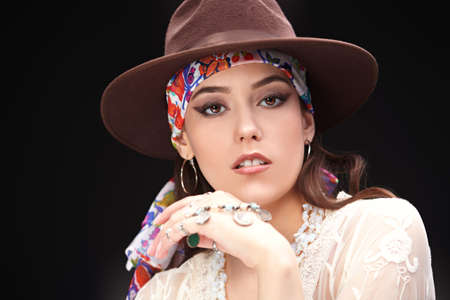 Portrait of a modern girl wearing hat and white lace dress on a black background. Summer fashion. Boho, modern hippie style. Copy space.の写真素材