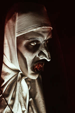 Close-up portrait of a devilish scary nun with terrible teeth. Halloween and Horrors.の写真素材