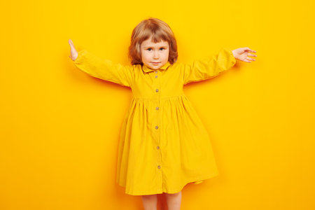 Portrait of a lovely little child girl spreading her arms to the sides and smiling. Happy childhood....