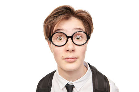 Emotional teen boy in school uniform and glasses looks at camera and surprised. School and Education. Studio portrait on a white background.の写真素材