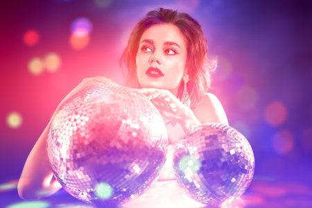 Portrait of a glamorous young woman with evening make-up and hairstyle posing in jewelry with disco...