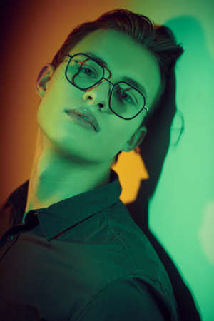 Unhappy handsome young man he looks aat camera in dark green lighting. Feelings and emotions.の写真素材