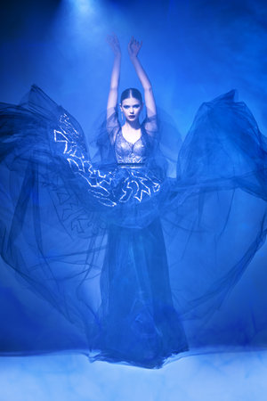 Fashion and beauty. Gorgeous fashion model girl poses in motion in a luxury evening dress. Full...