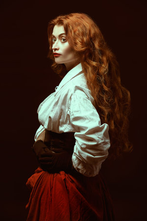 Beautiful young woman with magnificent red hair in a historical costume of 16-17th centuries. Studio...
