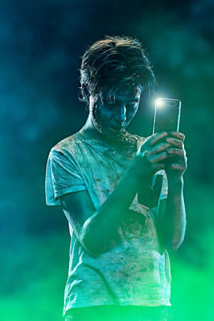 Halloween. Scary zombie boy teenager makes selfie on his smartphone.の写真素材