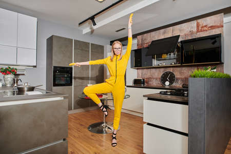 Super woman on her kitchen. Pretty girl poses with bananas at home in the kitchen. Modern interior, furniture for the kitchen. Cook at home. Healthy eating and diet.の写真素材