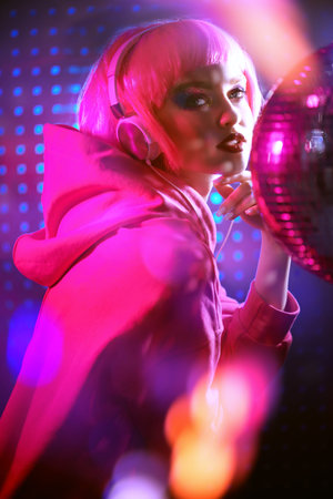DJ girl. Attractive girl with bright glitter make-up and pink hair poses with disco ball and...