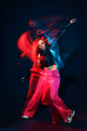 Contemporary dances. Professional hip hop dancer girl dancing at studio in neon light.の写真素材
