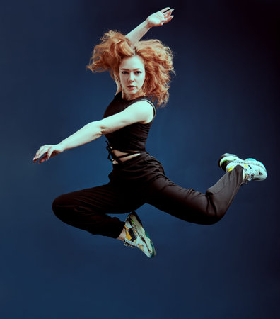 Professional modern style dancer jumping at studio on a dark blue backgroundの写真素材