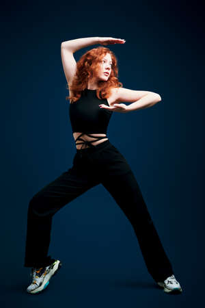 Modern dance style. Professional modern style dancer girl dancing at studio on a dark blue backgroundの写真素材
