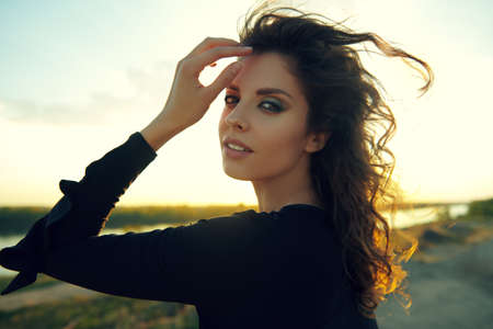 Portrait of a beautiful brunette woman against the backdrop of a landscape with sands and a river. Beauty, make-up.の写真素材