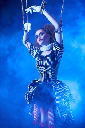 The actress plays a doll on strings at a performance in a puppet theater. A portrait in retro style.