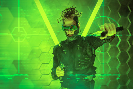 Militant cyberpunk warrior in a protective suit fights with guns in his hands in neon light. World of the future. Game, virtual reality.の写真素材