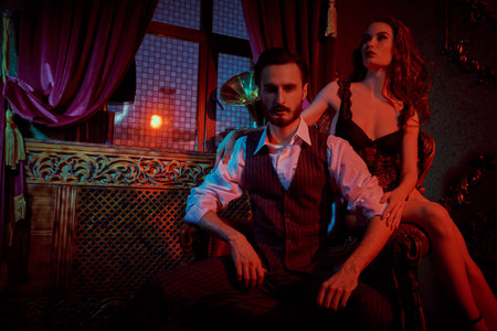 Glamorous couple in love. Beautiful lady in sexual black lingerie and a handsome man in elegant suit...