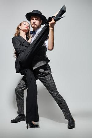Beautiful couple of young people in love dancing passionate tango. Sexual girl and handsome man in love. Fashion and love. Full length portrait on a gray background.の写真素材