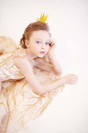 Charming little girl princess wearing evening dress and a crown. Kid's fashion. Studio portrait on a white background.の写真素材