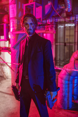 Courageous action hero with automatic guns in an industrial zone at night. Handsome wounded man special agent.の写真素材