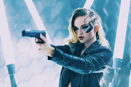 Sci-fi cyborg soldier girl. An attractive girl cyberpunk stands on alert with a gun among the neon lights. World of the future. Game, virtual reality.の写真素材