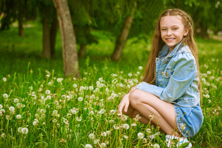 Happy summer holidays. Full length portrait of a lovely girl in denim clothes having a rest in a summer park.の写真素材