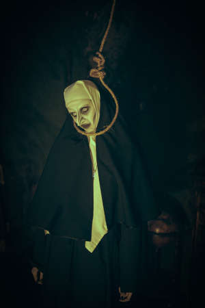 Portrait of a scary cursed nun standing in the abandoned chapel with a loop for hanging on her neck. Horrors. Halloween.の写真素材