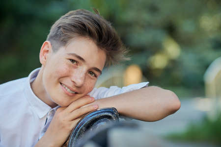 Happy teenage boy sitting in the park on a sunny summer day and smiling.の写真素材