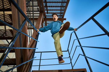 Emotional boy teenager stands on the metal stairs and takes a step forward. Young modern generation.
