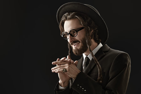 The Jew rubs his palms in anticipation of a good deal. Rich Jew concept. Studio shot on black...