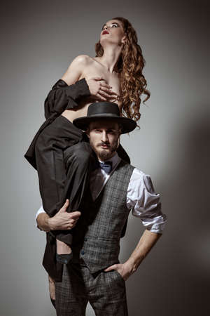 Love and fashion. Handsome passionate man in elegant suit holding a naked girl in his arms.の写真素材