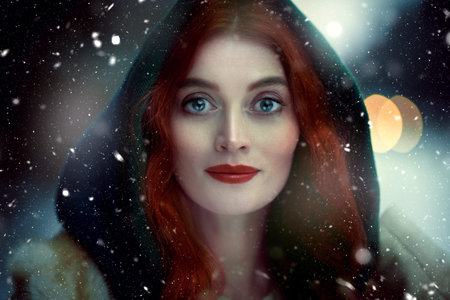 Close-up portrait of a beautiful young woman with red hair wearing medieval clothes hooded under the...