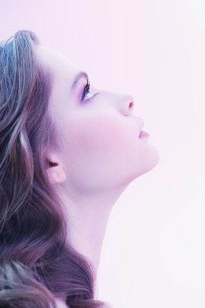 Beauty care, healthcare. Portrait of a beautiful tender girl with fresh clear skin, gentle lilac-violet makeup and wavy blonde hair looking up away.の写真素材