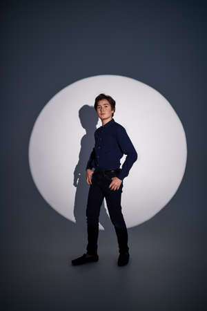 Full length portrait of a handsome boy teenager in a circle of light at the studio. Youth fashion.の写真素材
