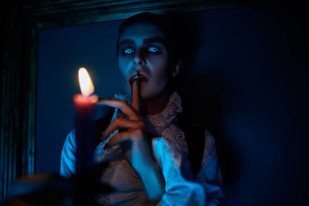 Scary vampire grins at a candle sneaking around the castle in the night in search of a victim. 19th century style. Halloween.の写真素材