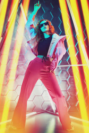 Beautiful young dancer girl dancing in neon light. Modern dances. Disco. Hi-tech dance style.の写真素材