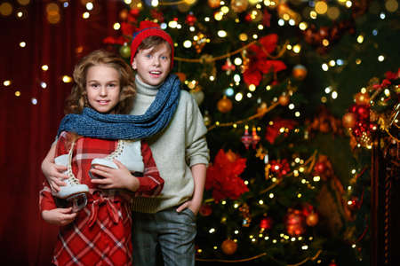 Merry Christmas and Happy New Year! Happy kids celebrate Christmas by a beautiful Christmas tree at home. Children's party.の写真素材