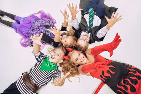 Happy Halloween! Cheerful children in carnival halloween costumes lie on the floor and stretch their hands up.の写真素材