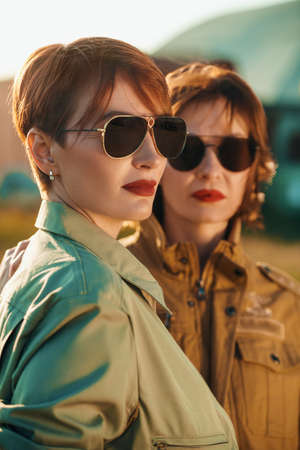 Two beautiful professional female commercial aviation pilots in stylish uniform and sunglasses with bright red lips posing at the airport. Aviation.の写真素材