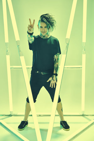 Full length portrait of a cool expressive punk rock musician with dreadlocks and in black clothes,...