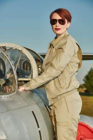 Professional commercial pilot woman wearing a uniform and sunglasses posing at the aircraft cockpit before taking off. Aviation.の写真素材