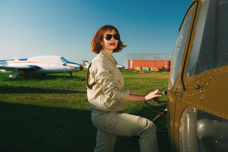 Portrait of a smiling professional helicopter pilot with bright red lips and black sunglasses posing...