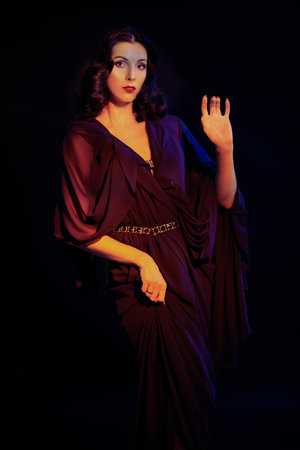 Portrait of a stunning feminine young woman posing in a black background in a retro style evening dress. Beauty and fashion of the 30s-40s.の写真素材