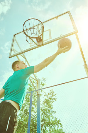 Basketball game. Athletic male basketball player trying to throw a ball into the basket during...
