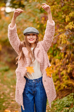Happy autumn days. Pretty and joyful young woman walking under a leaf fall in a beautiful autumn...