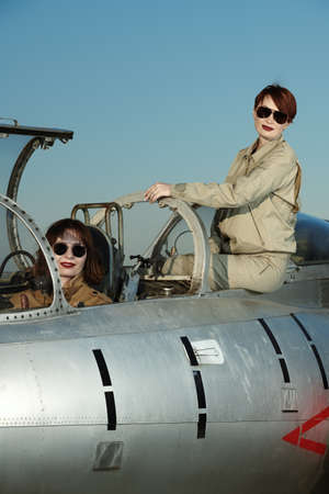 Professional commercial pilots women wearing uniform and sunglasses pose sitting in their aircraft cockpit before taking off. Women in aviation.の写真素材