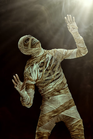 Portrait of a scary evil mummy on a dark background seeing a mysterious light coming from above....