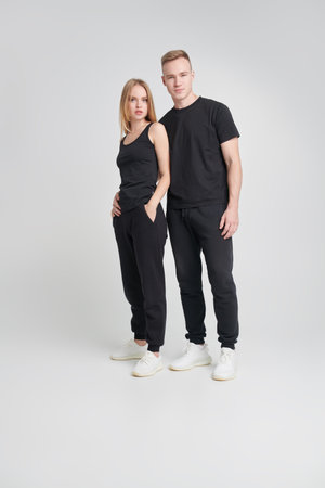 Full length portrait of a happy beautiful girl and young man in love in black sportswear posing on a...