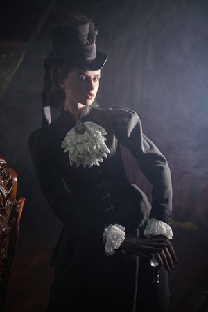 Elegant beautiful young woman  in a 19th century dress posing in a dark vintage room full of smoke....