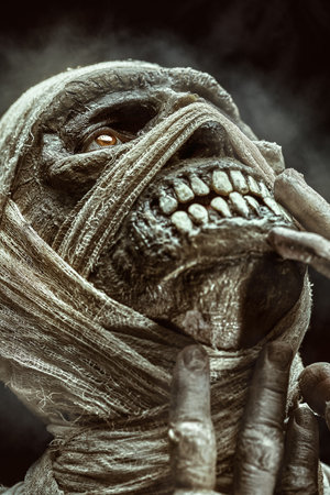 Close-up portrait of a scary mummy being tortured by his burning flash. Black studio background. Halloween. Ancient Egyptian mythology.の写真素材